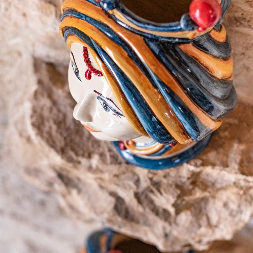 Handmade ceramic Testa di Moro head vase in blue and orange, displayed on stone