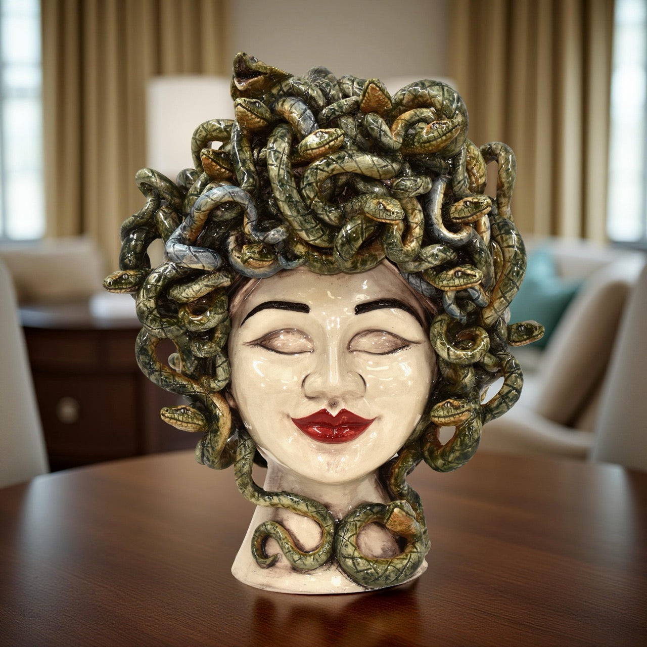 Handcrafted ceramic Medusa head sculpture with snakes and red lips on table