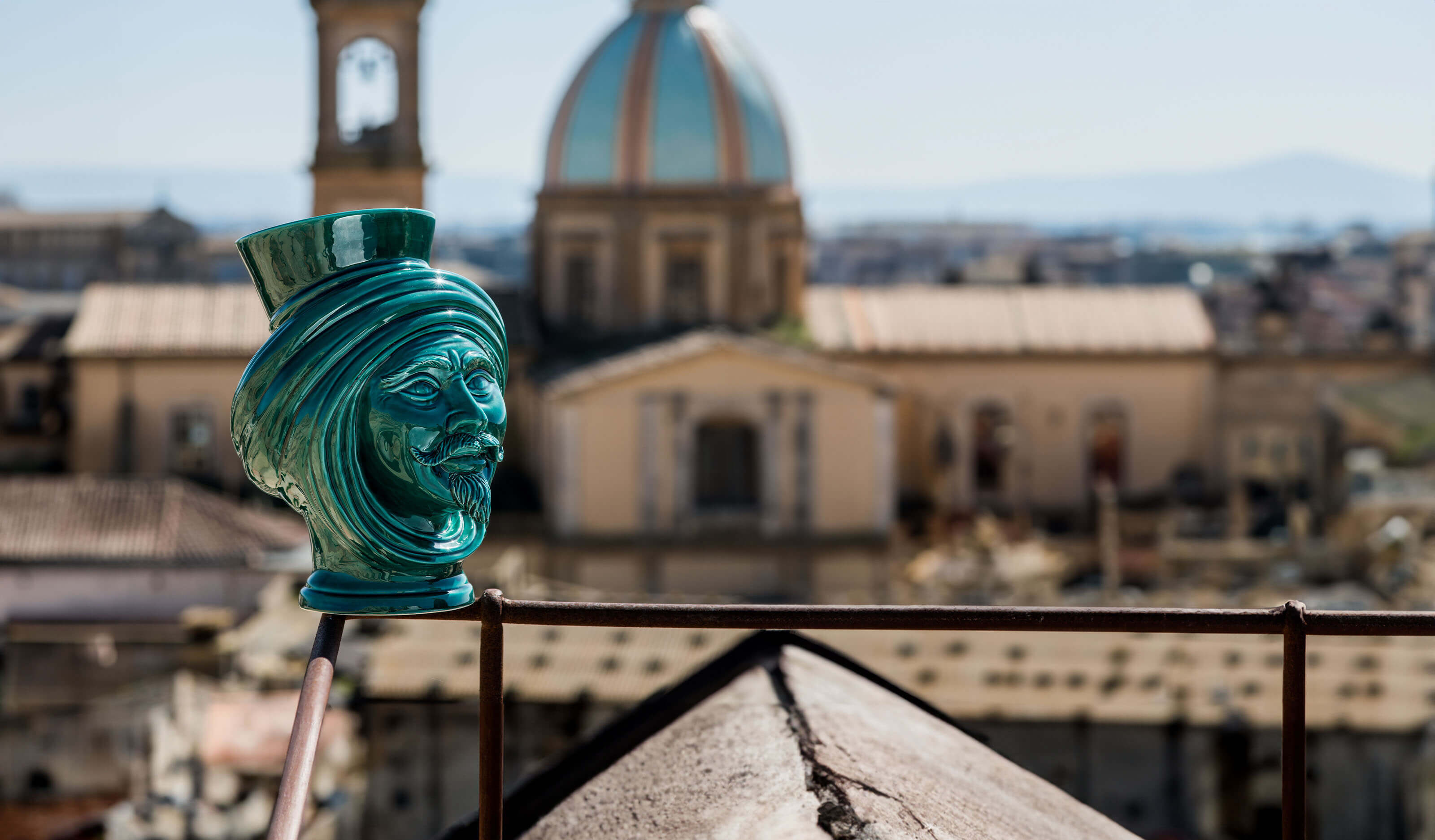 Handcrafted green ceramic Testa di Moro vase on a rooftop with cityscape background