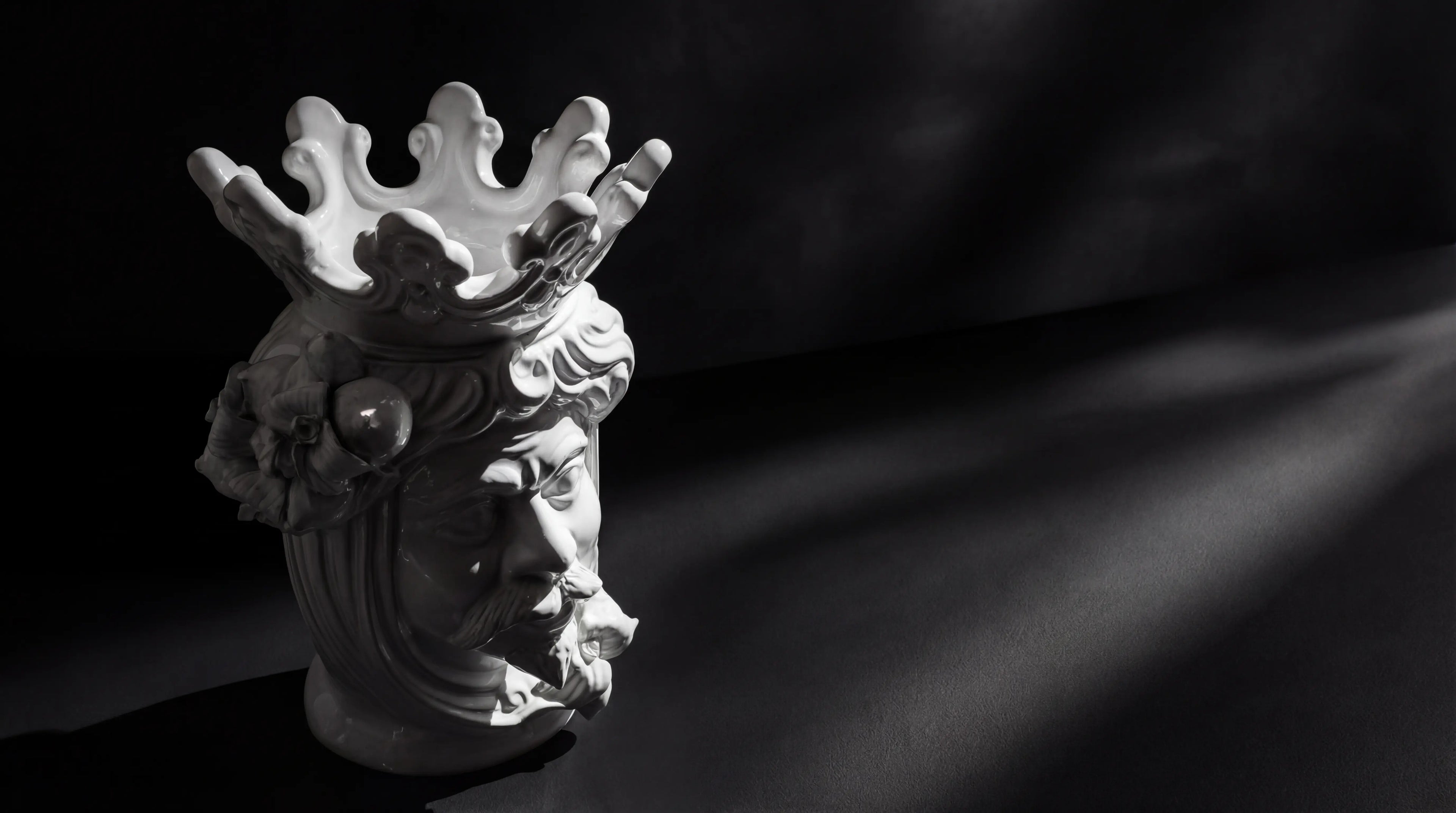 White ceramic Teste di Moro vase with crown, floral details, and bearded face, modern design on dark background