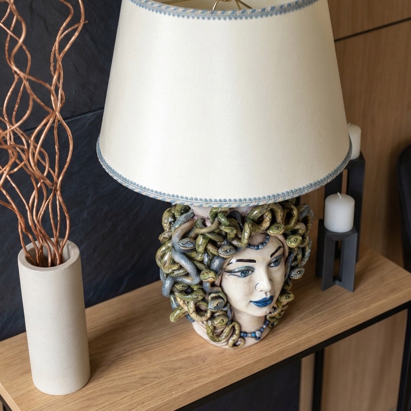 Handmade Medusa head table lamp with snake hair, blue accents, and cream shade on wooden console
