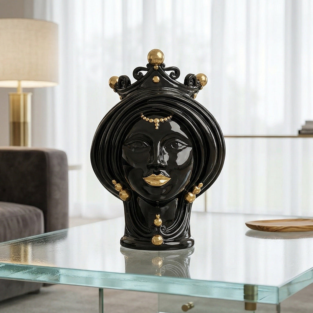 Black and gold Teste di Moro decorative head sculpture with crown, displayed on glass table in modern living room