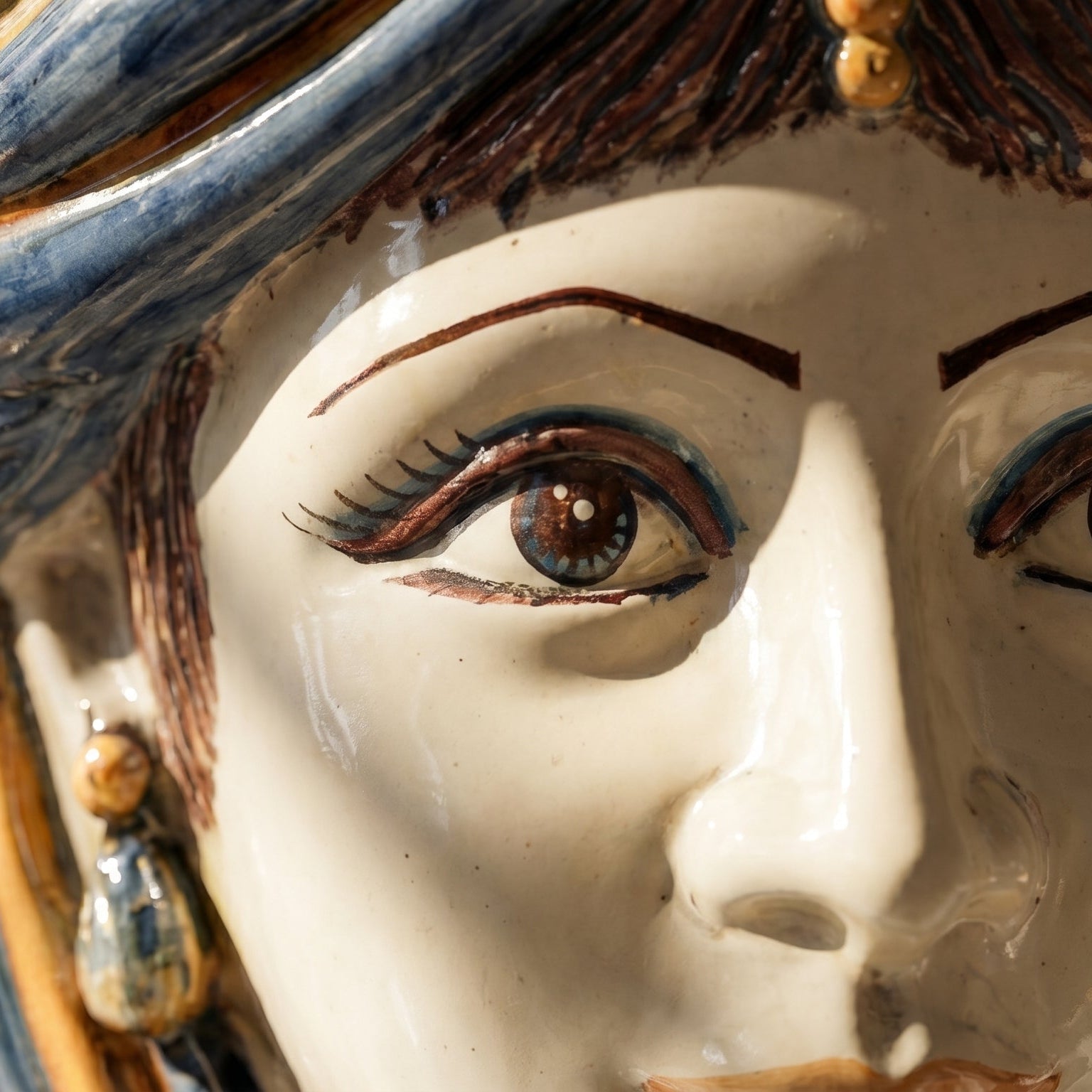 Close-up of a handcrafted Testa di Moro ceramic face with detailed painted eyes and expressive features.