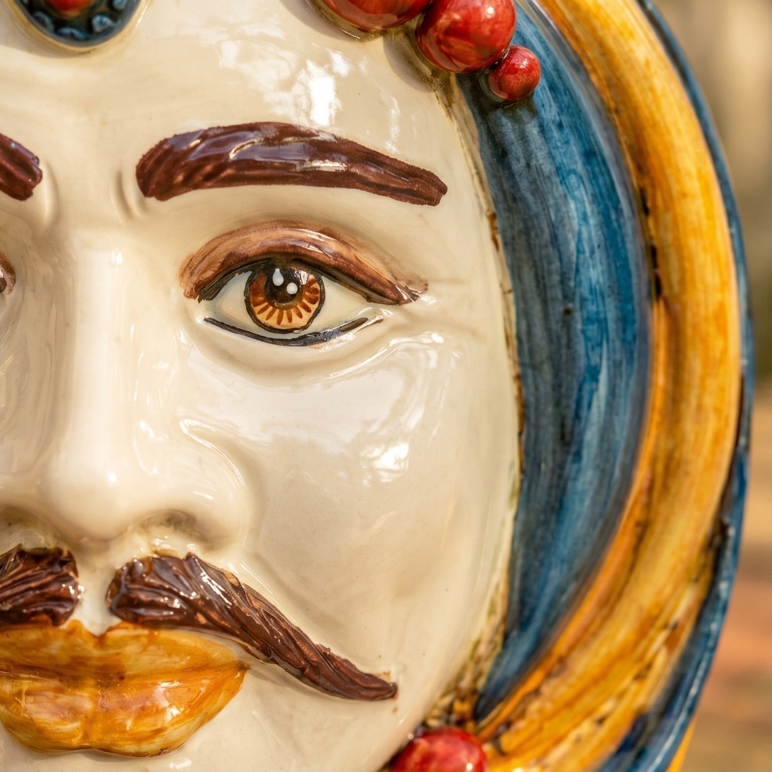 Handcrafted Teste di Moro ceramic face with detailed eye, mustache, and vibrant blue and gold accents