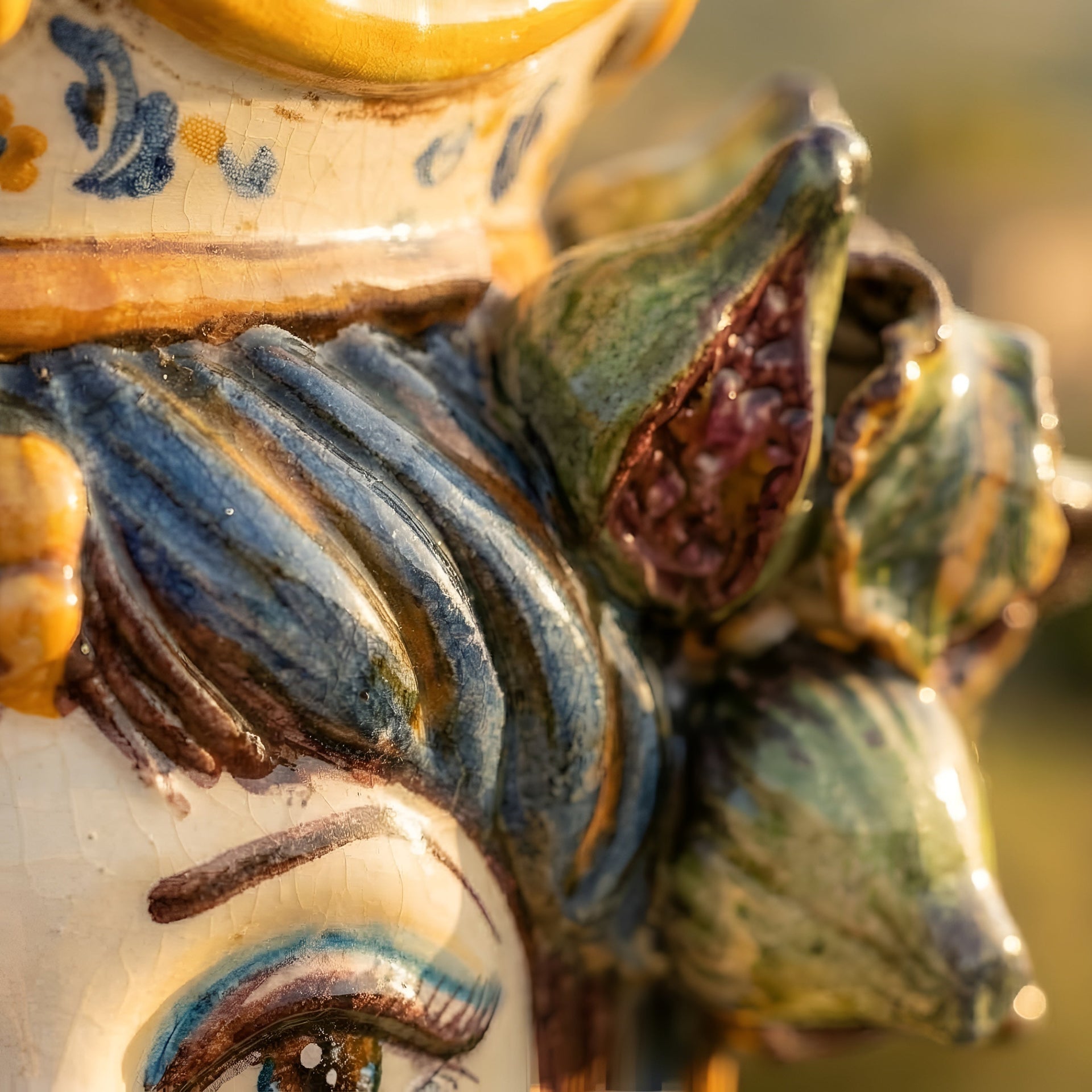 Hand-painted ceramic Testa di Moro with vibrant blue, green, and yellow glaze, showcasing intricate floral details and traditional Sicilian artistry.