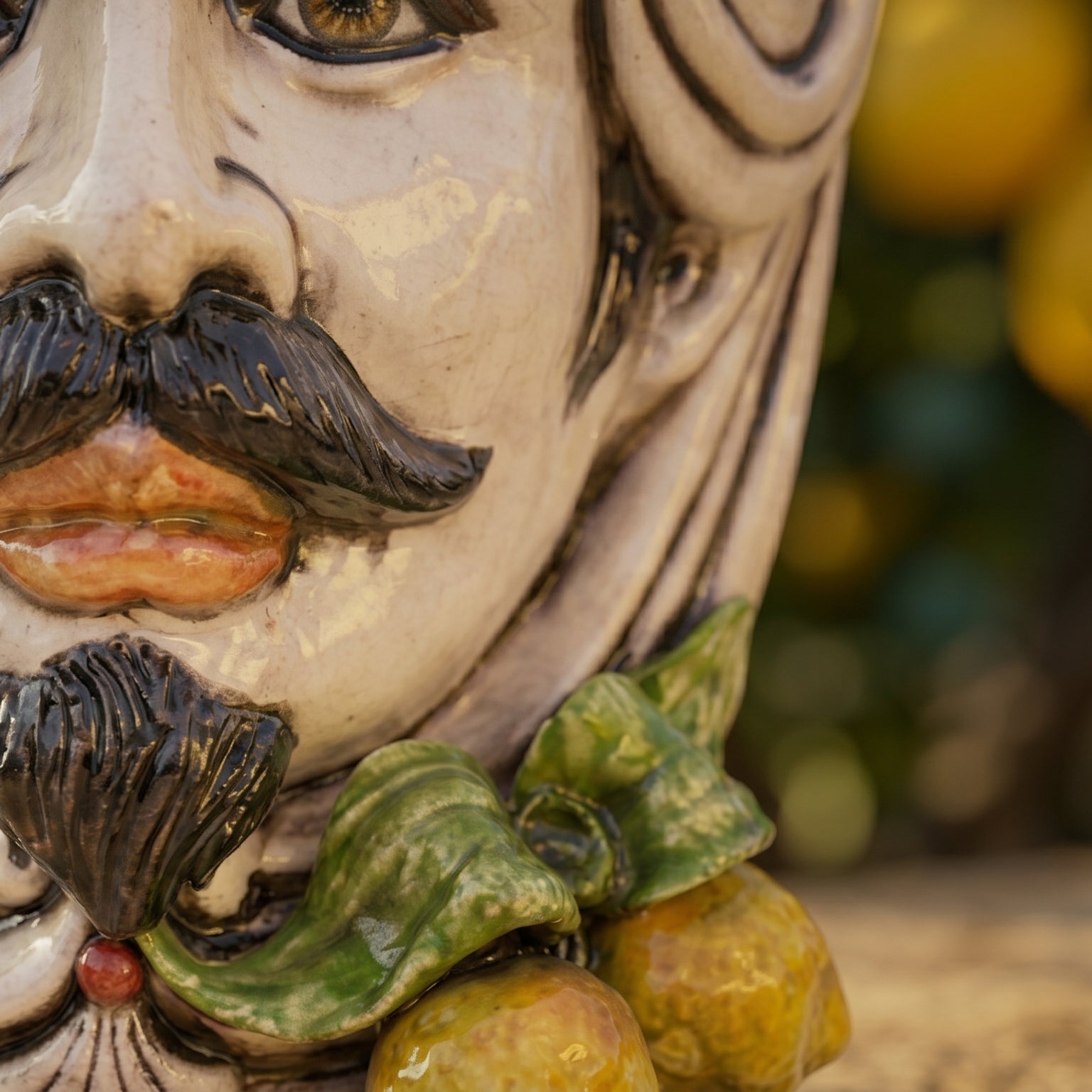 Handcrafted Teste di Moro ceramic face with mustache, green leaves, and citrus fruits, blending tradition and modern design.