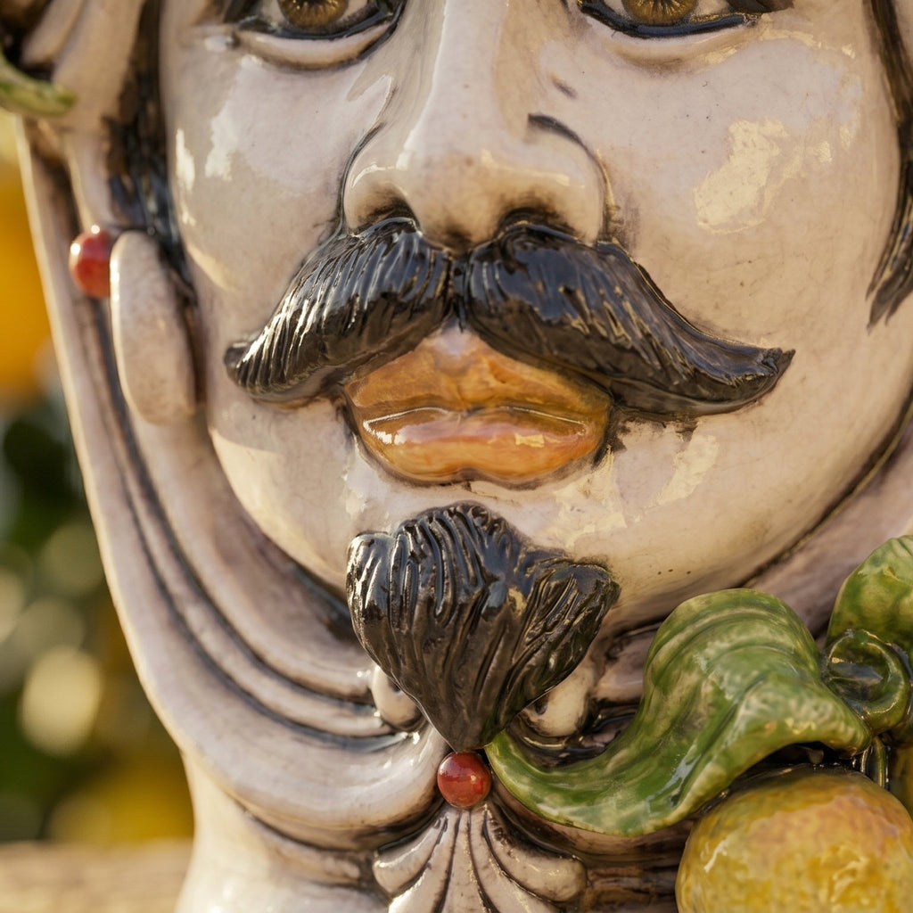 Handcrafted Teste di Moro ceramic face with mustache, green leaves, and fruit, blending tradition and modern design.