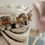 Handcrafted ceramic vase with floral details and amber accents, blending tradition and modern design.