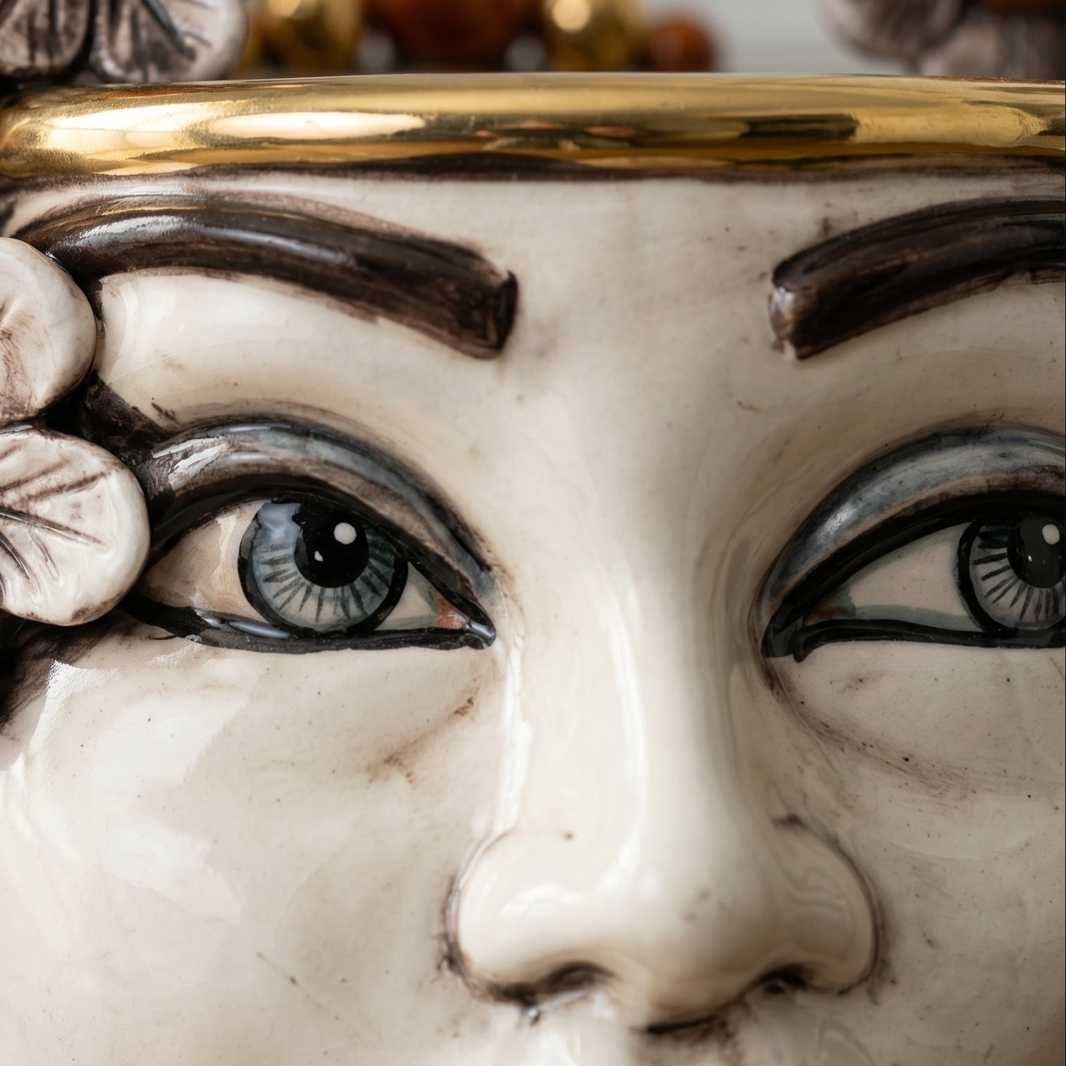 Handcrafted Teste di Moro ceramic face with expressive blue eyes, gold rim, and floral detail
