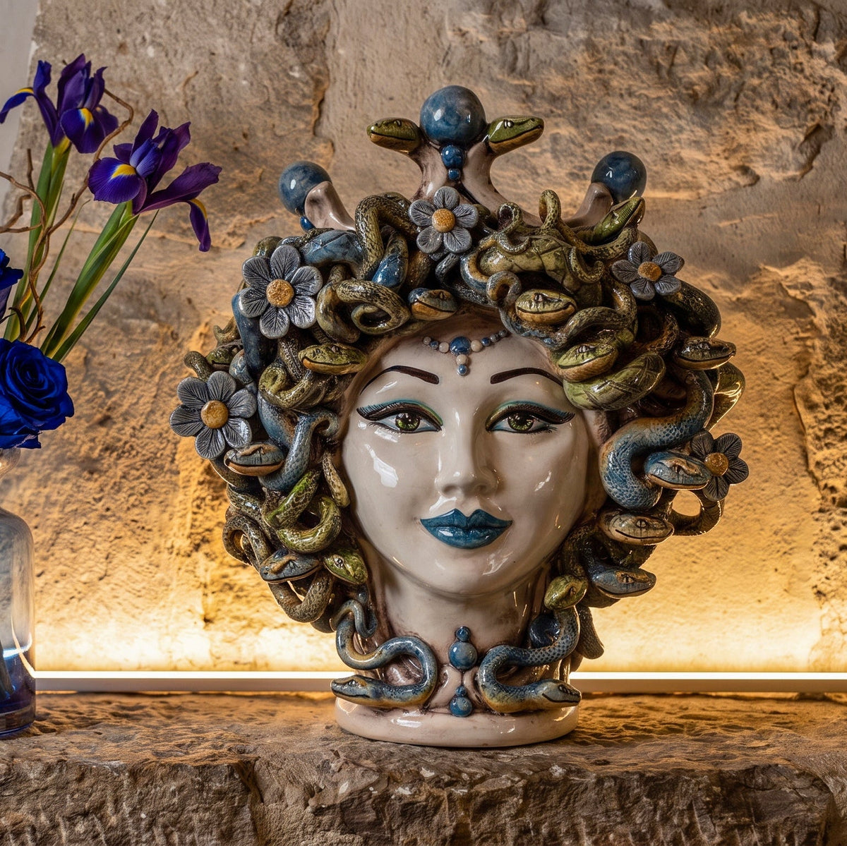 Medusenkopf H 30 cm mit Blumen, beleuchtet in einer Steinnische mit blauen Iris