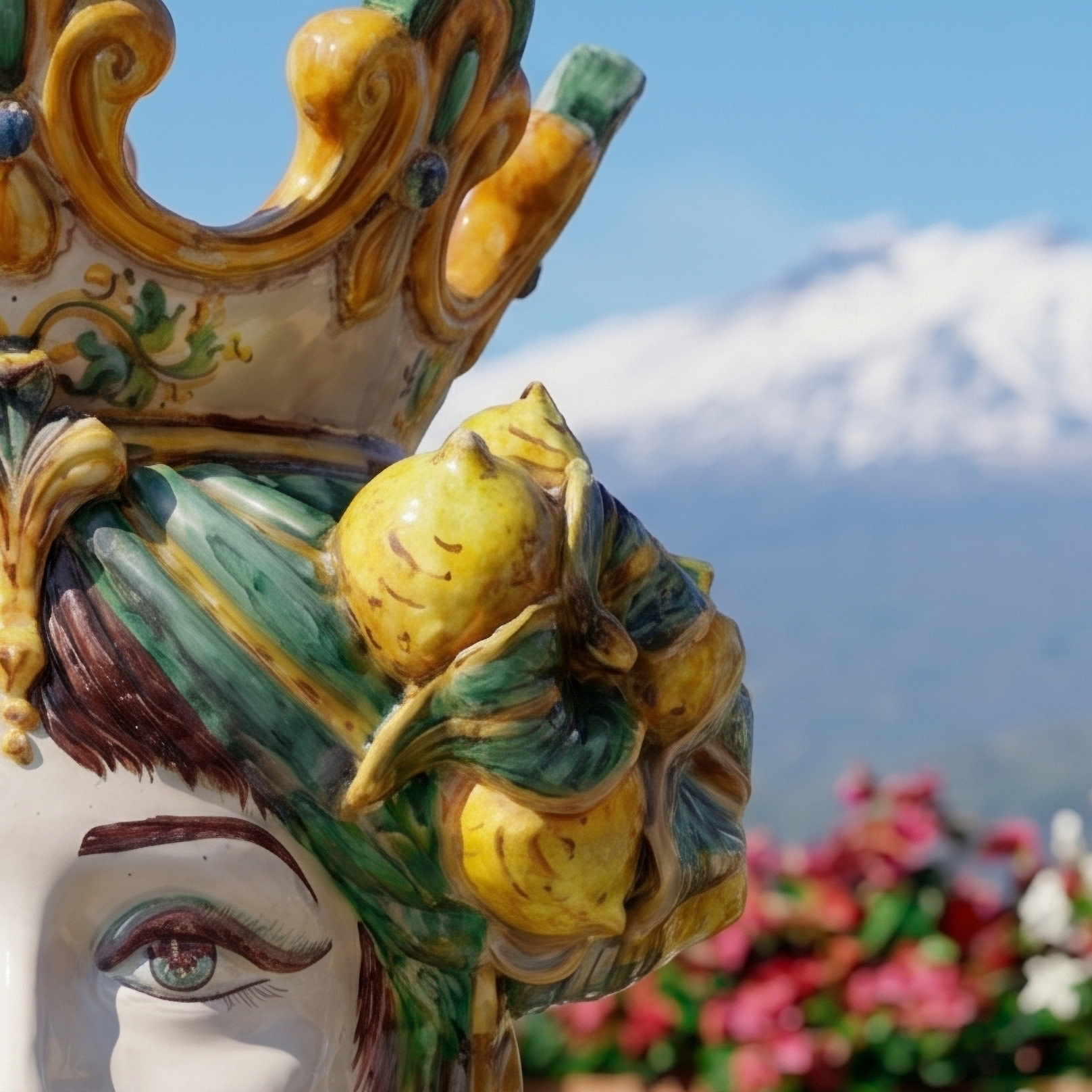 Handcrafted Teste di Moro ceramic with lemon adornment, vibrant colors, and mountain backdrop
