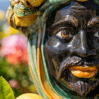 Handmade Teste di Moro ceramic face with vibrant glaze, lemon accents, and garden backdrop