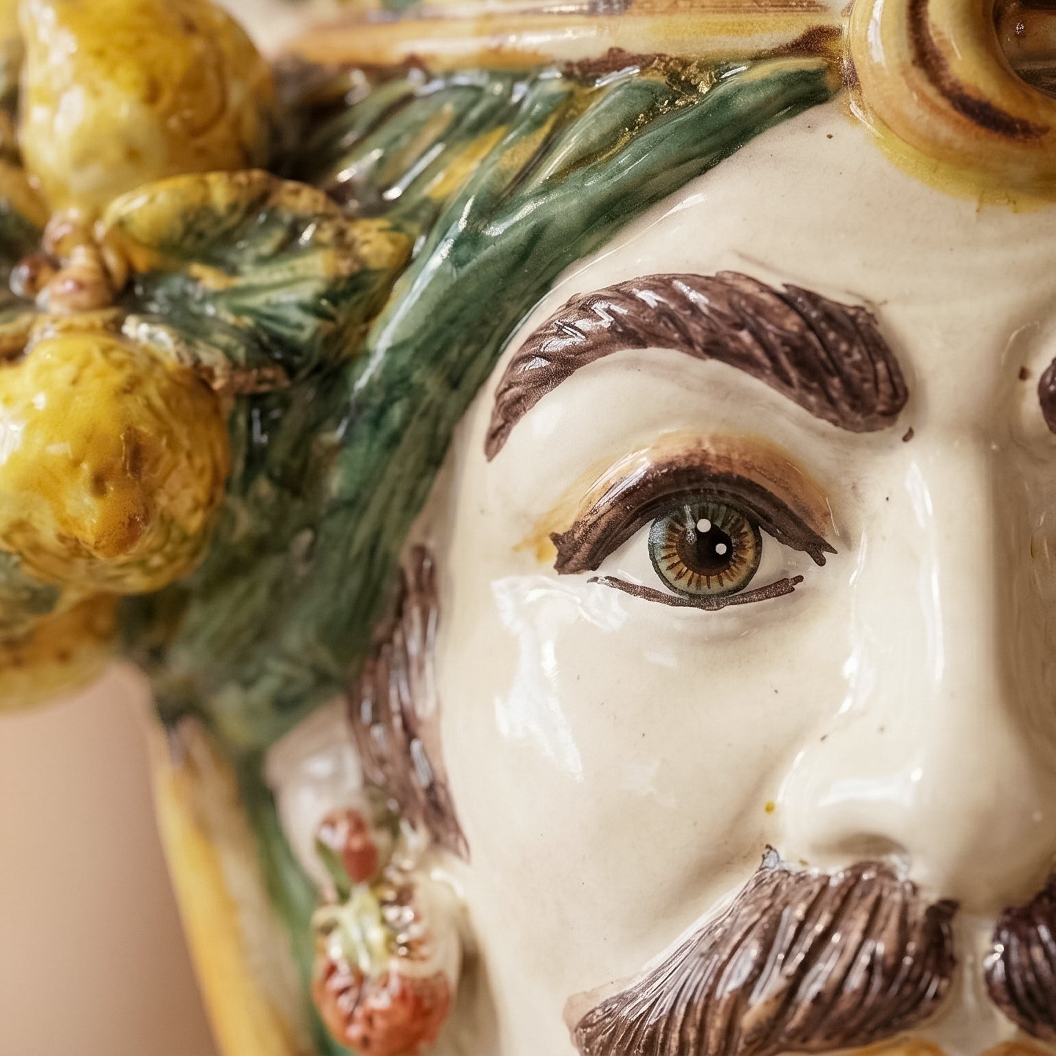 Handcrafted Teste di Moro ceramic with detailed eye, green leaves, and yellow fruit, blending tradition and modern design.
