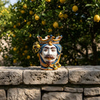Handcrafted Teste di Moro ceramic vase with crown, set against lemon tree backdrop, blending tradition and modern design.