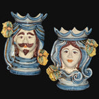 Handmade Teste di Moro ceramic vases with blue swirls, floral accents, and crowned faces—traditional Sicilian decor.