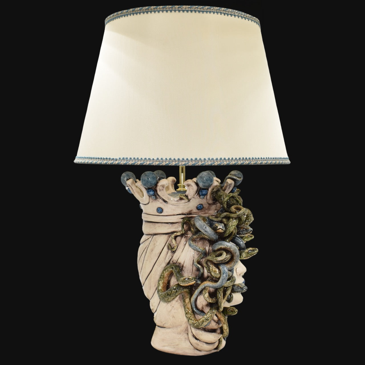 Handcrafted Medusa head table lamp with snake details and cream shade, blending tradition and modern design.