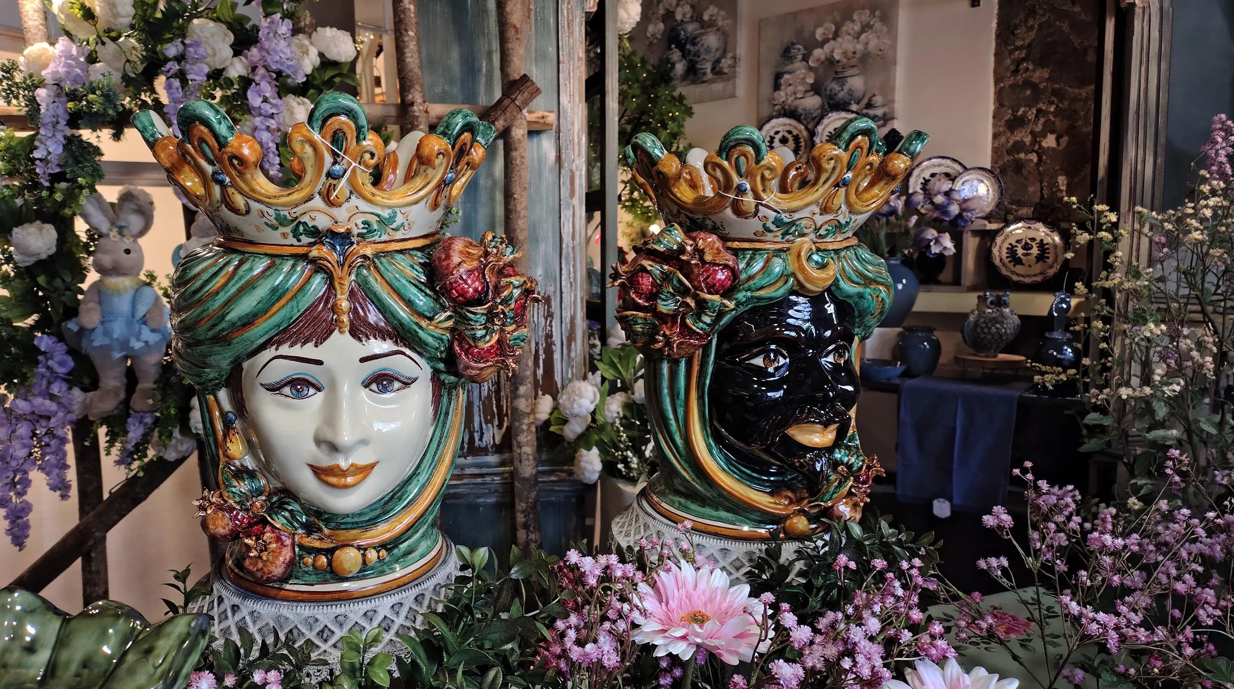 Handcrafted Teste di Moro ceramic heads with vibrant crowns, surrounded by flowers, blending tradition and modern design.