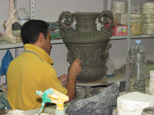 Artisan crafting a handmade Teste di Moro vase with intricate relief details in a pottery workshop