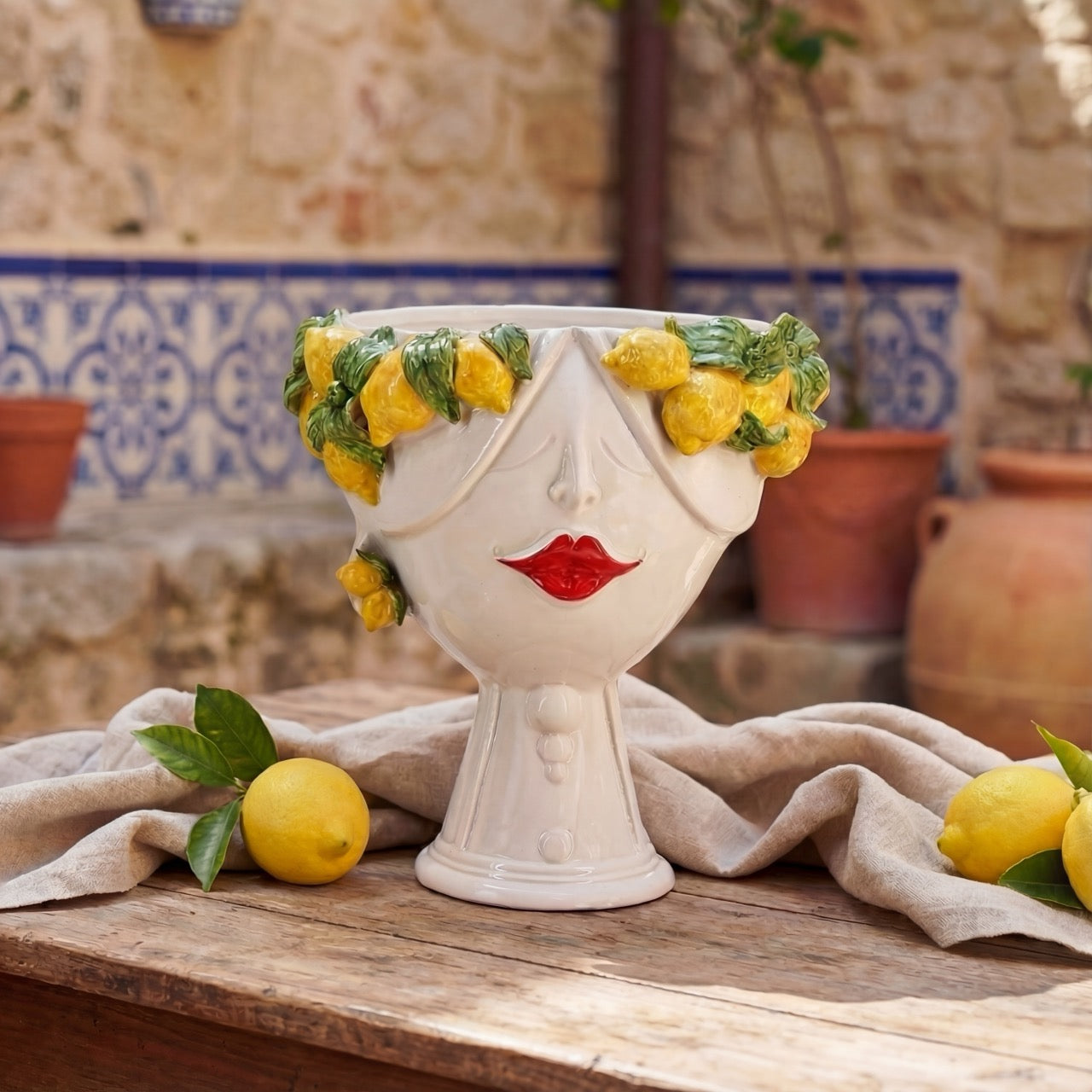 Handmade ceramic Testa di Moro with lemon wreath, red lips, on rustic table with lemons