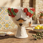 Handcrafted Teste di Moro planter with red roses, mustache, and beard, set on rustic table with Sicilian tiles