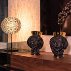 Handmade black ceramic Teste di Moro vases with gold accents, displayed on wood console with modern lamp