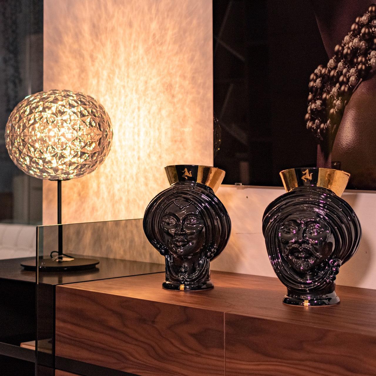 Handmade black ceramic Teste di Moro vases with gold accents, displayed on wood console with modern lamp