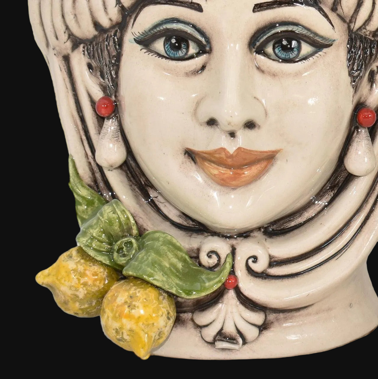 Handmade Teste di Moro ceramic face with blue eyes, red earrings, and lemon accents, blending tradition and modern design.