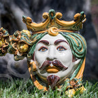 Handcrafted Teste di Moro ceramic face with crown, green hair, mustache, and floral details on grass