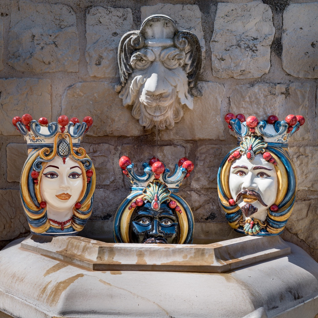 Handcrafted Teste di Moro fountain with colorful ceramic faces and stone lion head, blending tradition and modern design.