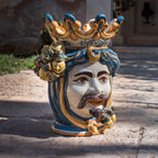 Handcrafted Teste di Moro ceramic vase with crown, vibrant blue and gold details, outdoor display