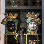 Handmade Teste di Moro ceramic vases with crowned faces, vibrant colors, displayed in shop window