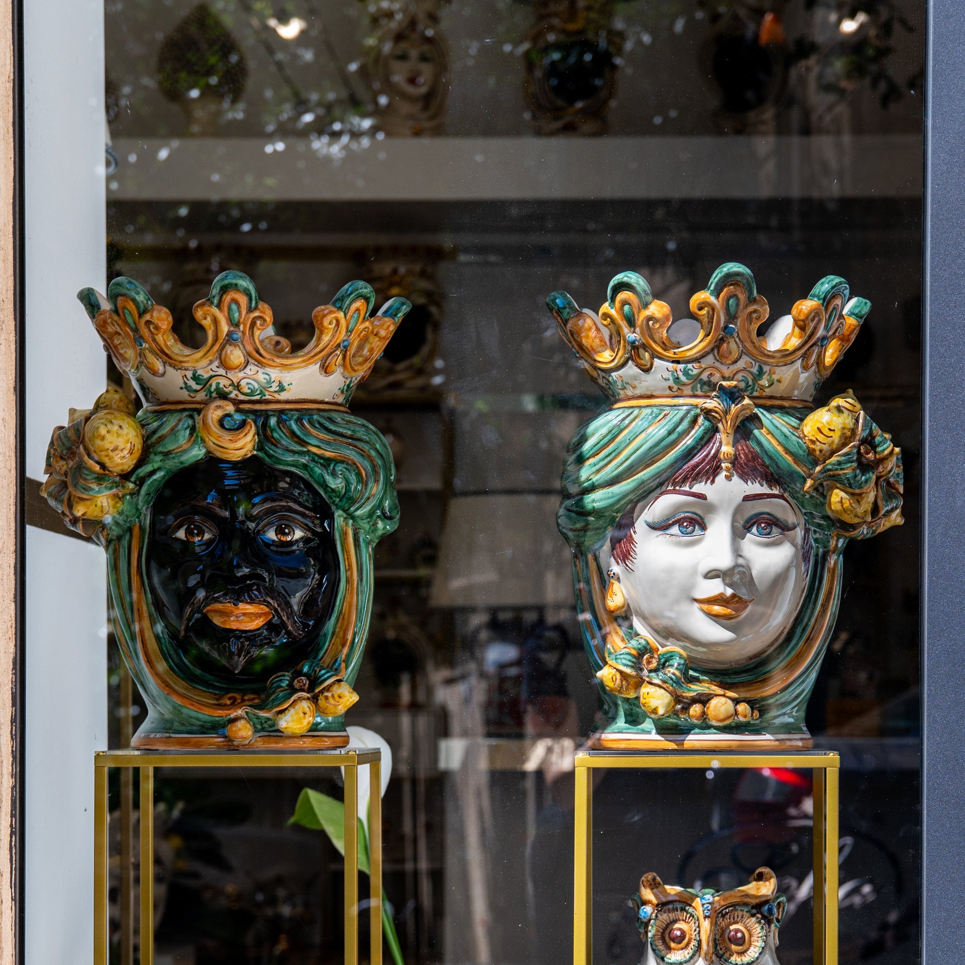 Handmade Teste di Moro ceramic vases with crowned faces, vibrant colors, displayed in shop window