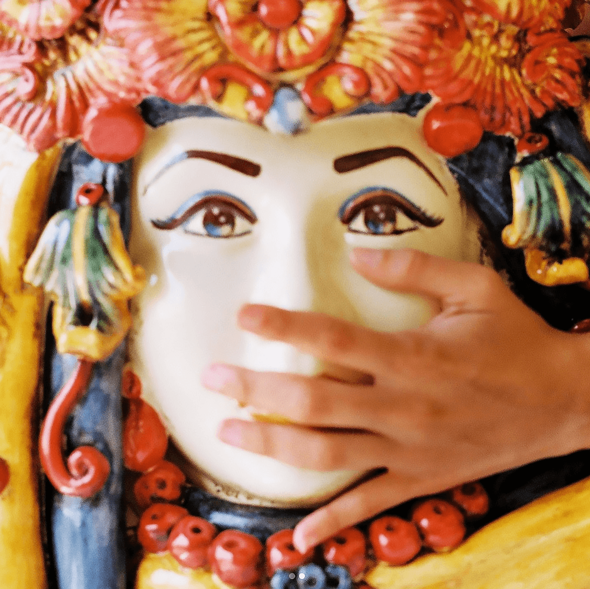 Hand touching a colorful Sicilian Testa di Moro ceramic head with floral turban décor