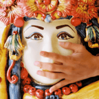 Hand touching colorful ceramic Testa di Moro with floral crown and vibrant details