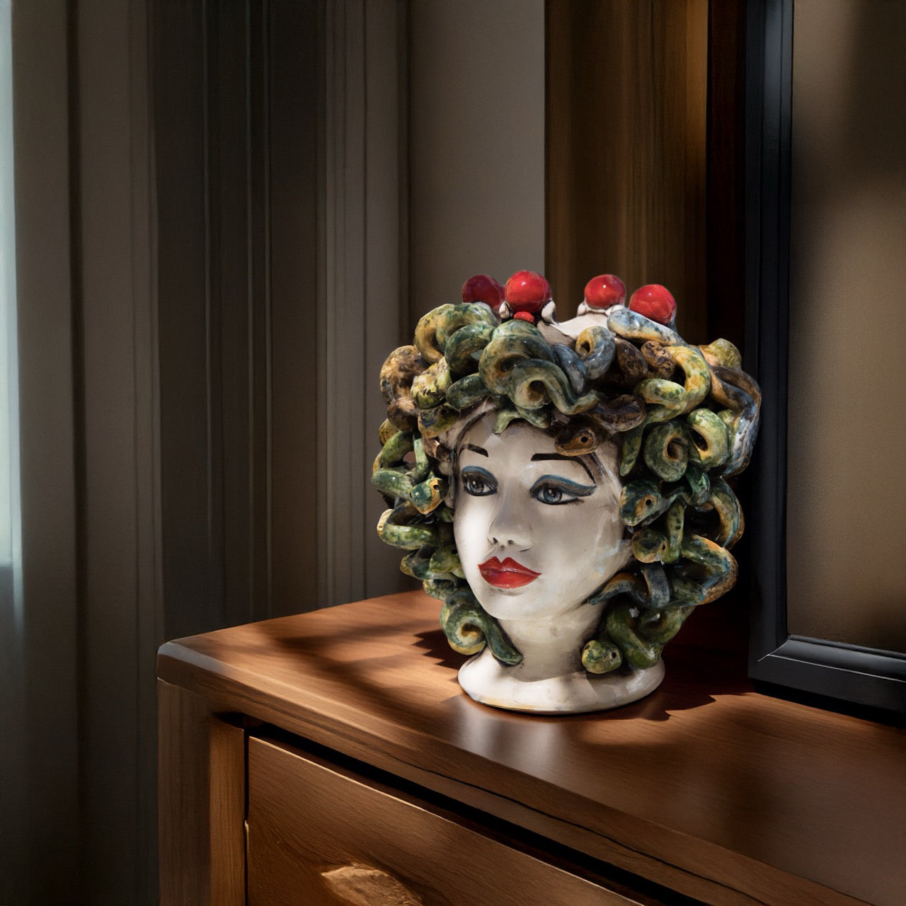 Handcrafted Teste di Moro ceramic sculpture with snake hair and red accents, displayed on wooden furniture